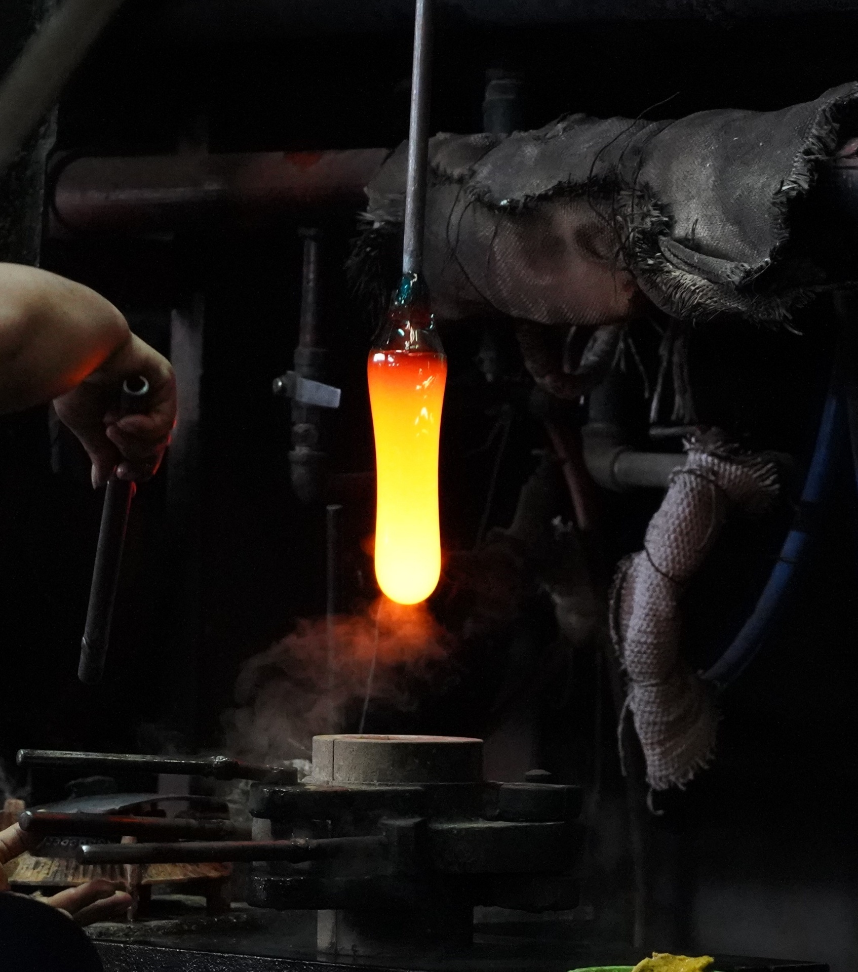 Glassblower shaping glowing molten glass